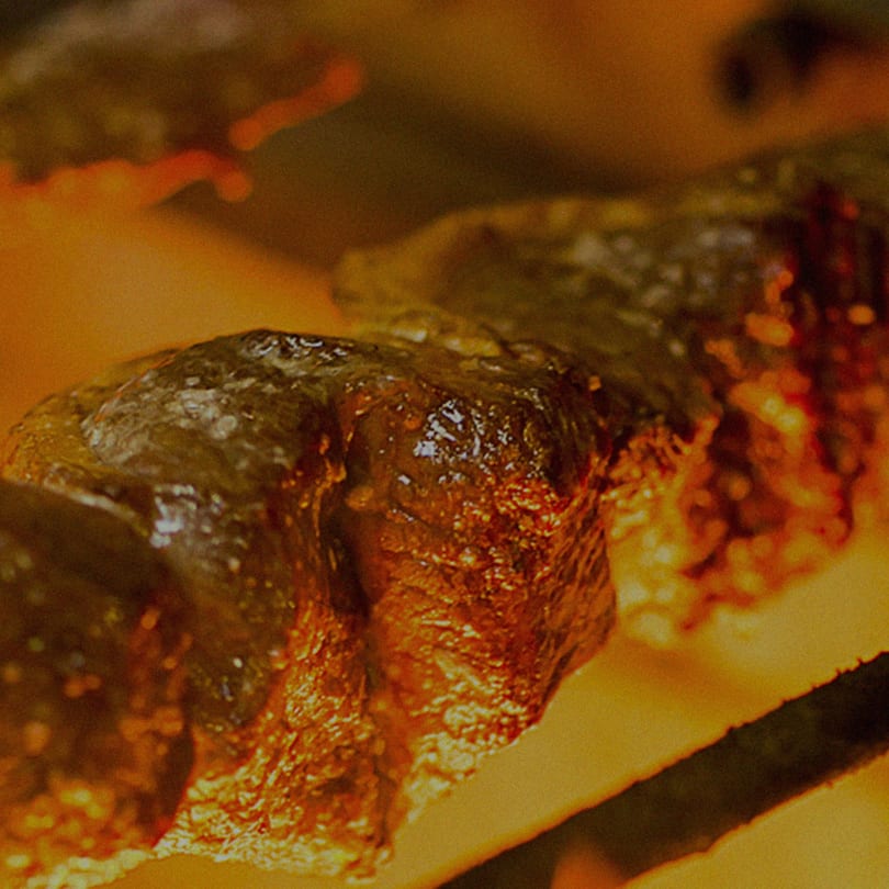 Close-up of Brazilian picanha steak cooking on a rotisserie skewer, glistening with juices.
